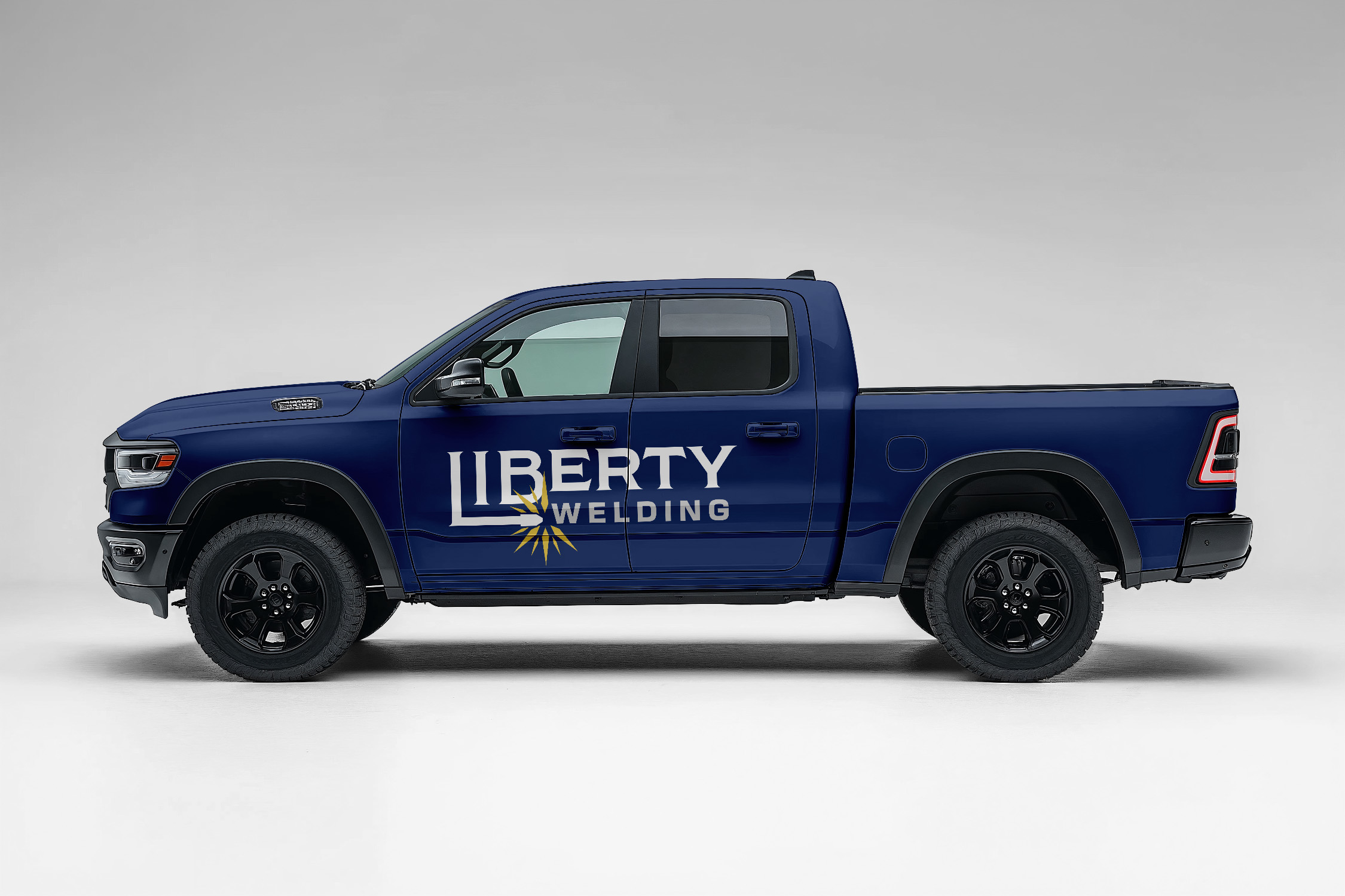 A dark blue pickup truck with the Liberty Welding logo across the driver door.